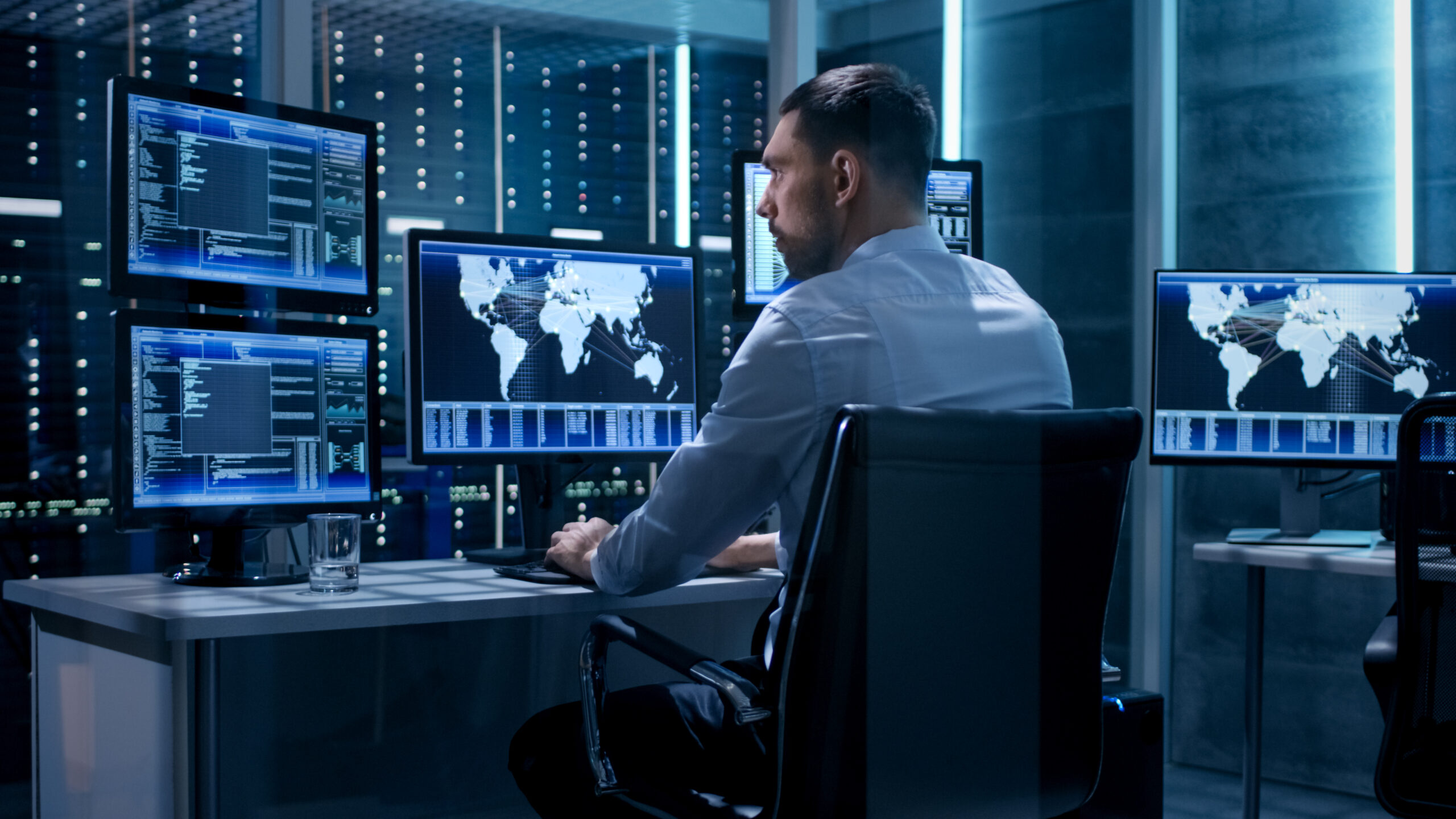 Technical Controller Working at His Workstation with Multiple Displays. Displays Show Various Technical Information. He's Alone in System Control Center. 